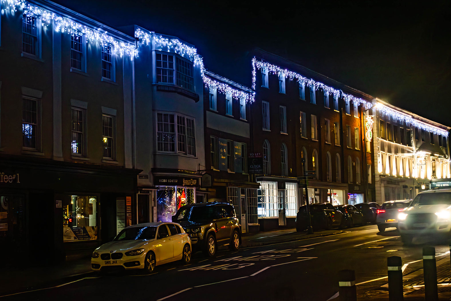 White icicle lights running along the top of buildings on a town centre street