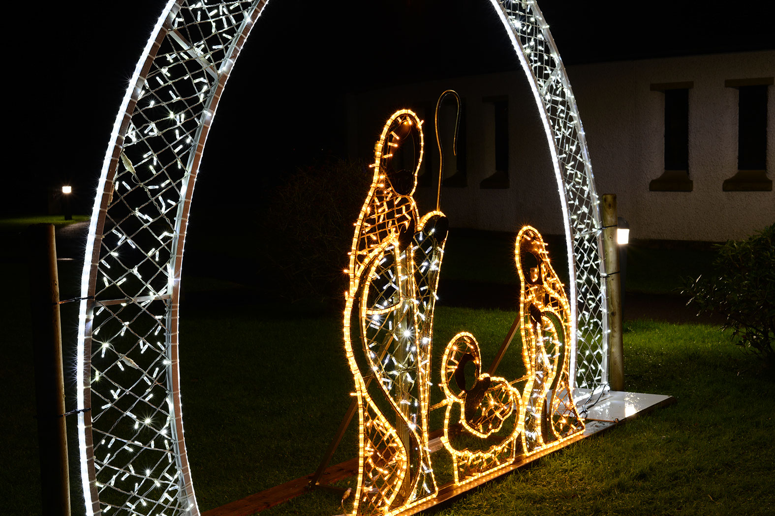 Close-up of illuminated nativity scene featuring Mary, Joseph, and Jesus under an arch