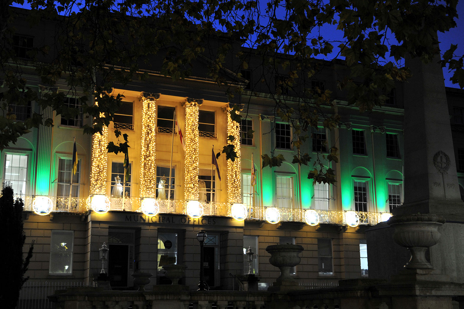 Close-up of a classical building illuminated with uplighters and light strings wrapped around the columns