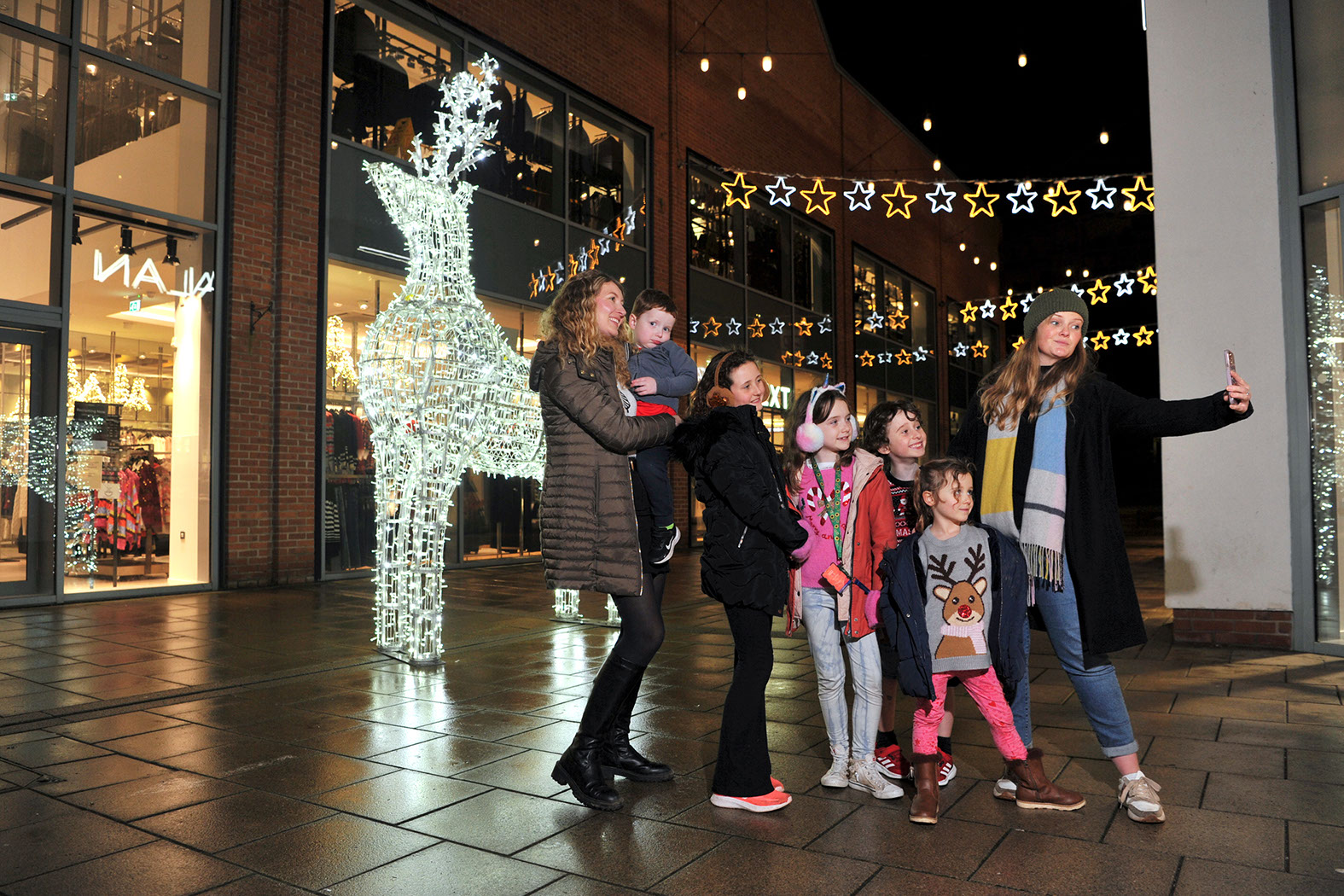 Large white illuminated reindeer with a family taking a selfie in front