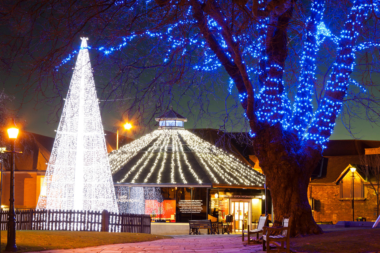 White blade cone tree with a blue light-string wrapped tree to the right