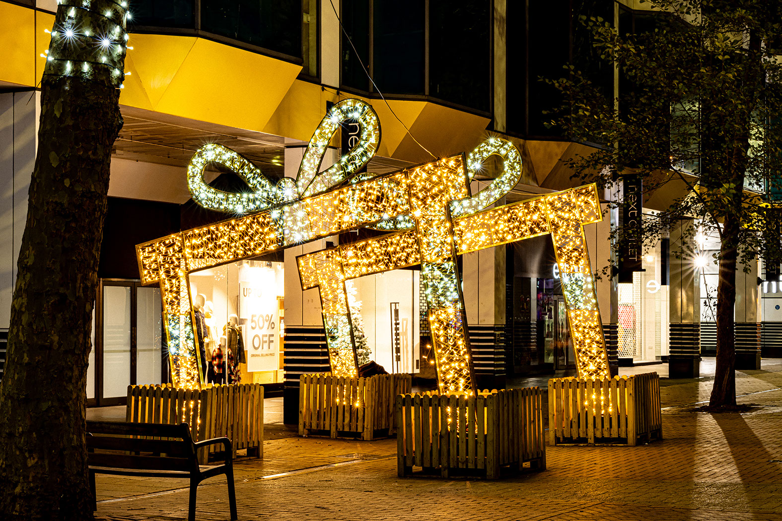 Two sloping gift box arches forming a walk-through path in a pedestrian shopping street