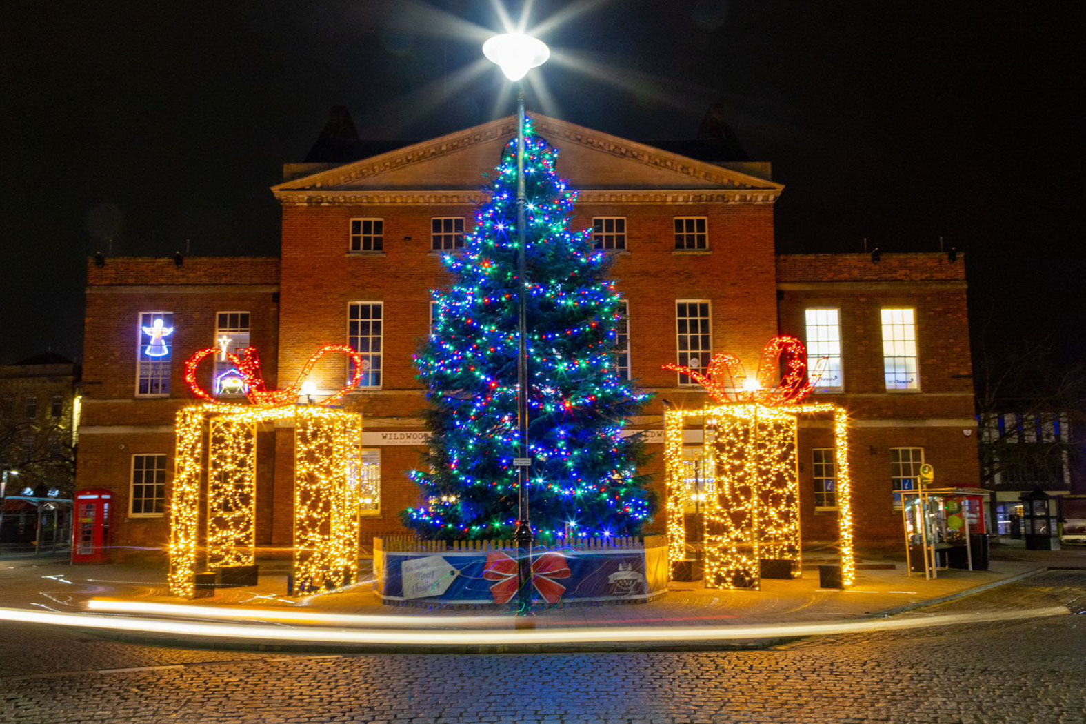 Large warm white walk-through gift boxes on either side of a Christmas tree