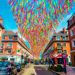 A street with a rainbow colored ribbon ceiling hanging above it.