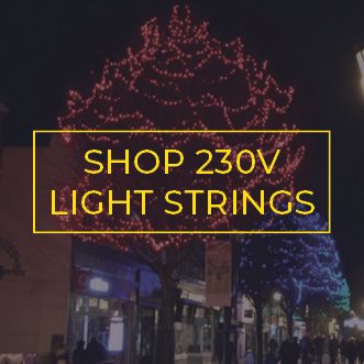 Brightly coloured commercial Christmas light strings wrapped around tree branches and canopy in a pedestrian town centre