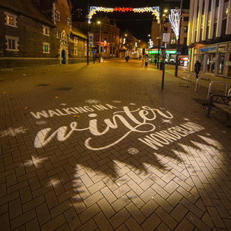 A brick sidewalk with a white GOBO projection that says 