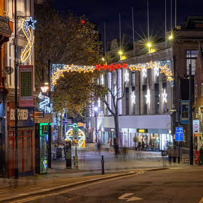 A nighttime street scene decorated with illuminated star-shaped Christmas lights hanging above the road.