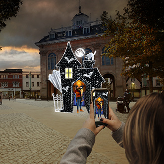A person is taking a picture of a Halloween display in a city.