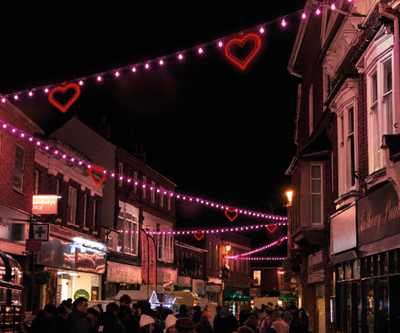 A row of streetlights illuminate a dark night sky with decorative semi-circular discs with stars as column motifs visible on the left side.