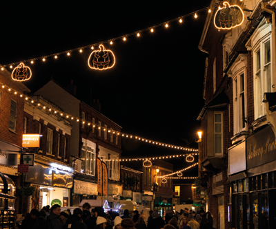 A nighttime street scene decorated with illuminated star-shaped Christmas lights hanging above the road.