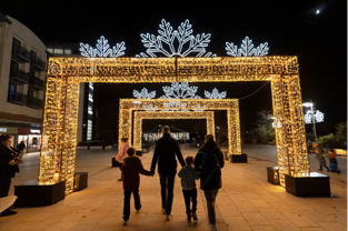 Three large warm white 3D Snowflake Gate arches with family of four walking underneath together