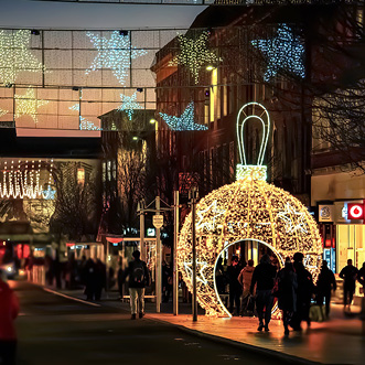 A busy city shopping street with an illuminated walk-through Christmas bauble and star lights above the street.