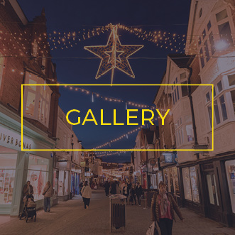 Commercial festoon lights with Christmas decorations spanning a busy shopping centre avenue