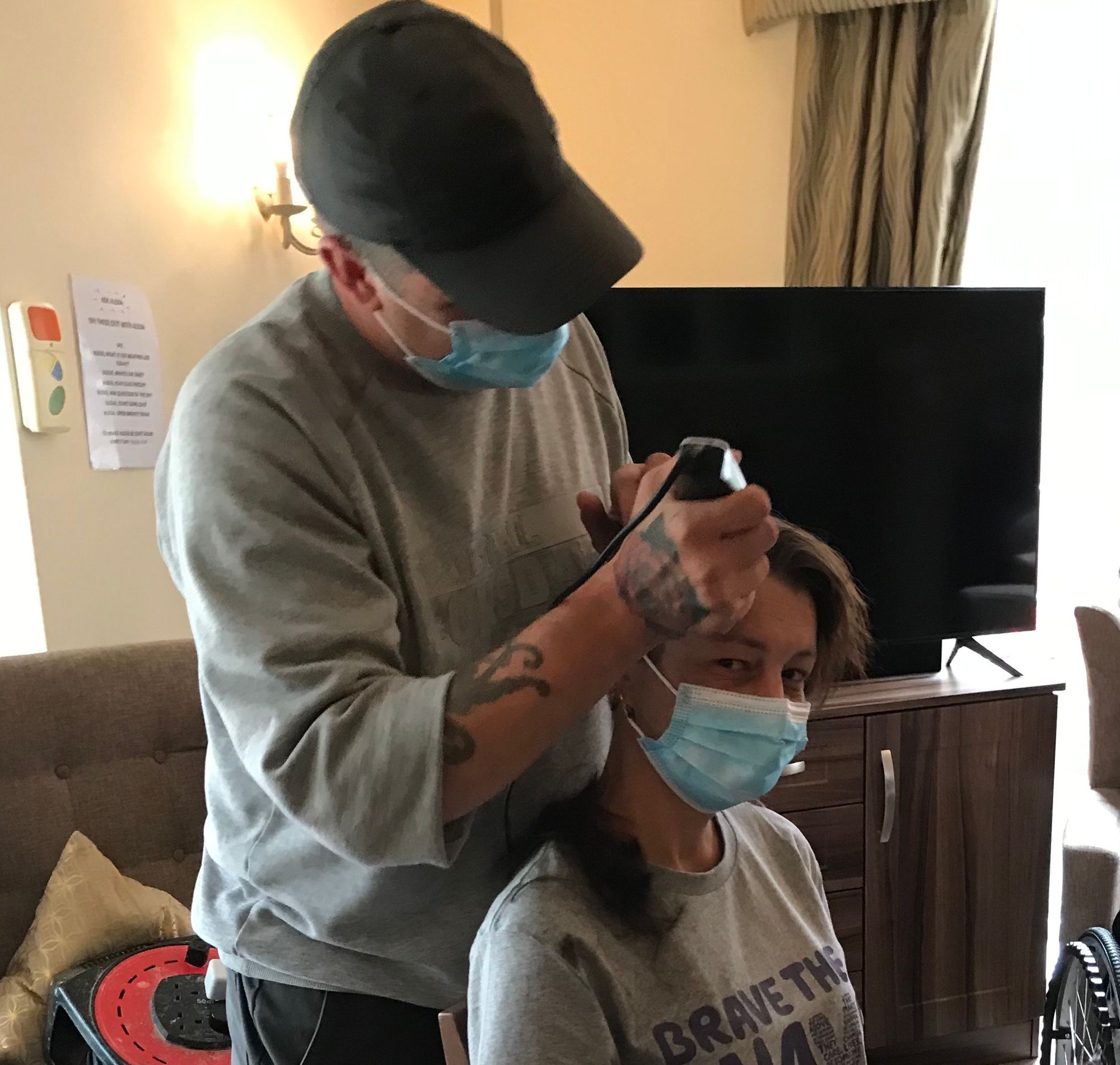 A picture of Sharon Gant having her head shaved by a man holding a shaver.