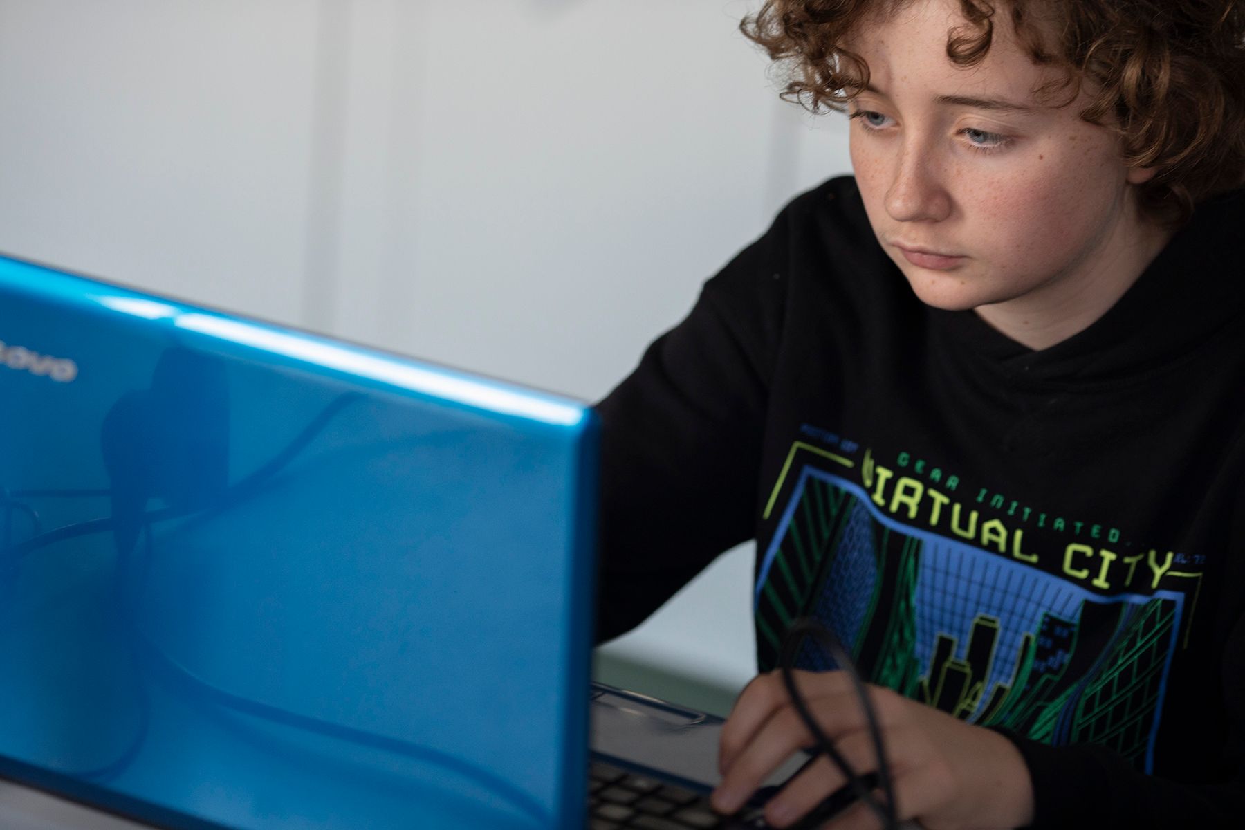 A boy sitting down using a laptop.