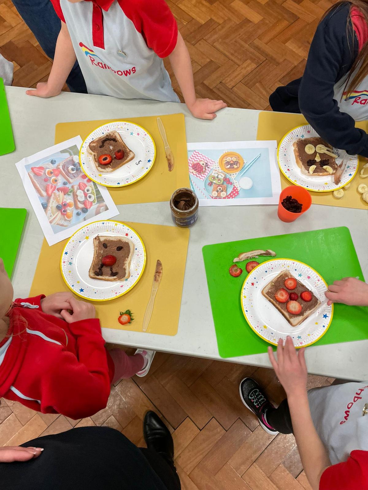 A table with paper plates and pieces of bread that have fruit on them to look like animal faces.