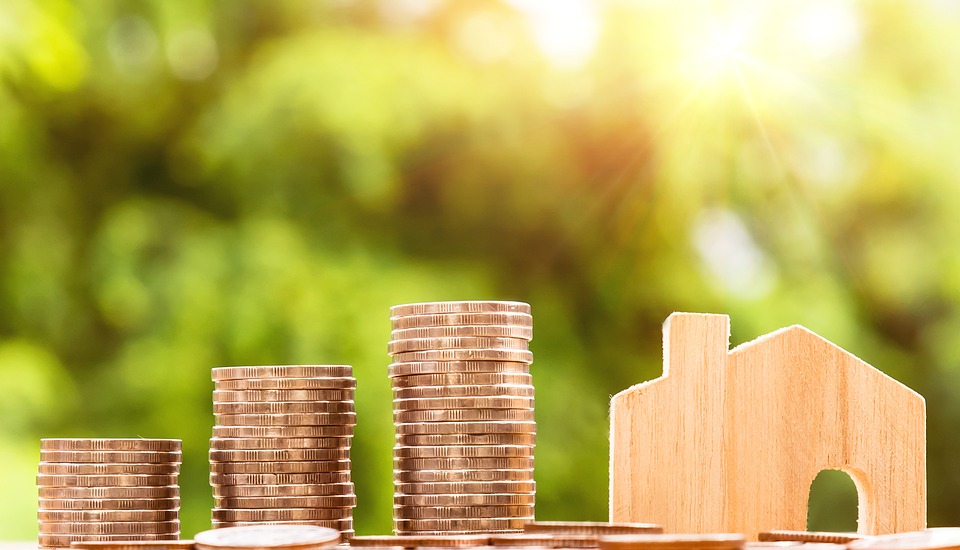 Tres montones de monedas se sitúan a la izquierda de una casa de madera