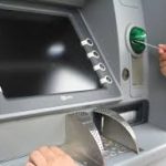 Una persona está introduciendo su tarjeta de crédito en un cajero automático para sacar dinero.