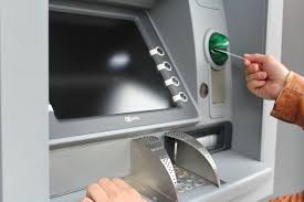 Una persona está introduciendo su tarjeta de crédito en un cajero automático para sacar dinero.