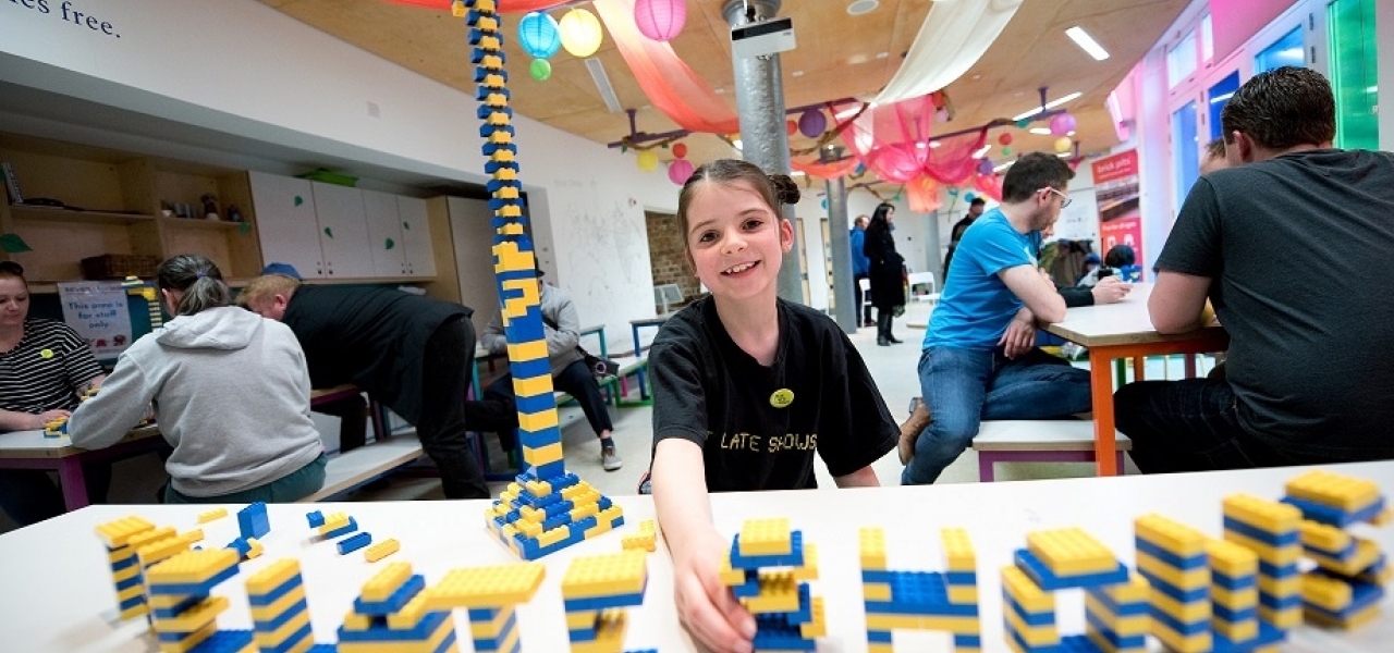 Young girl playing with yellow and blue lego.