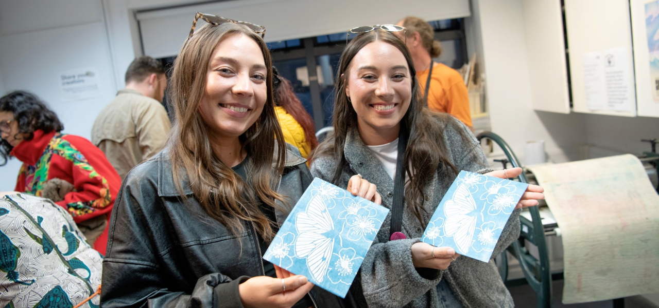 Two females in an artist study showing the prints they have made