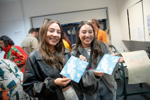 Two females in an artist study showing the prints they have made