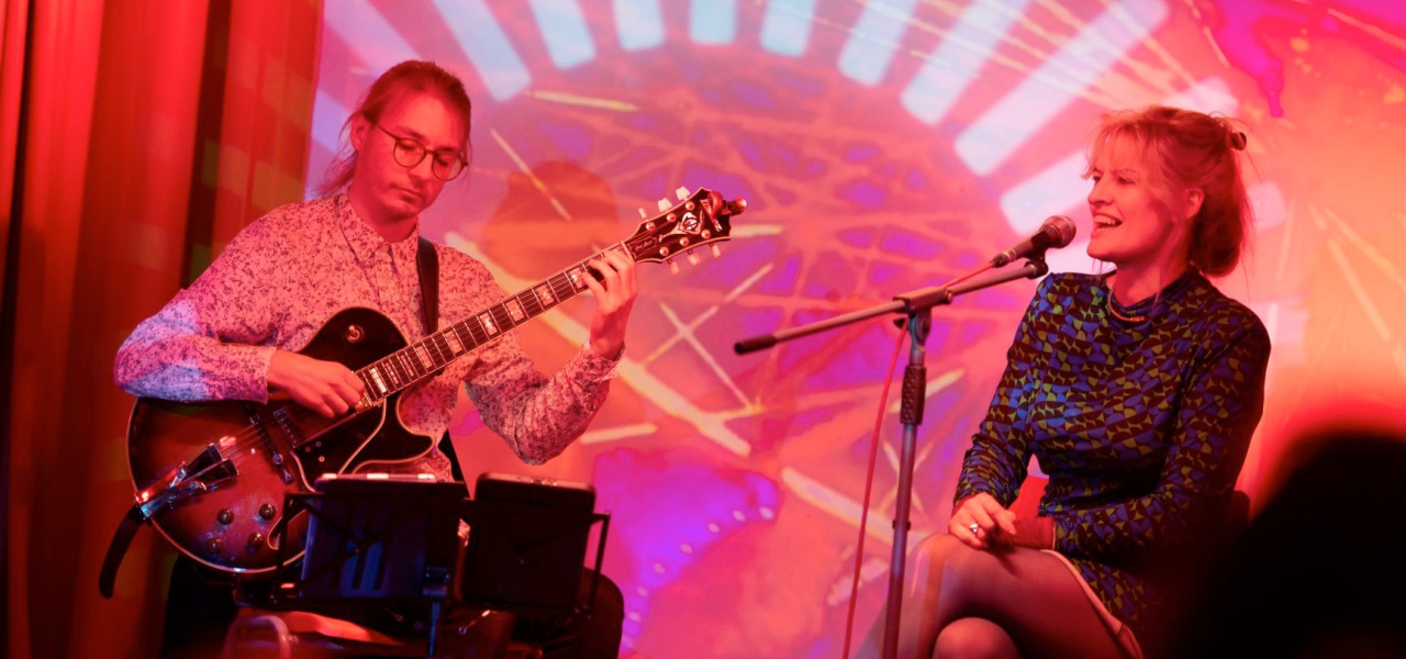 (c) Colin Davison. Photograph of 2 musicians performing on a colourful lit stage