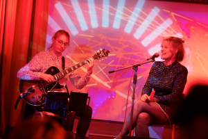 (c) Colin Davison. Photograph of 2 musicians performing on a colourful lit stage