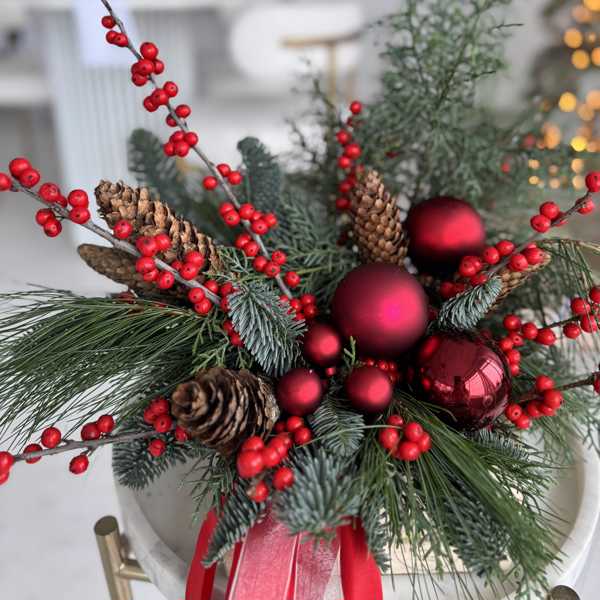 Рождественская композиция из илекса, зимнего декора и шишек