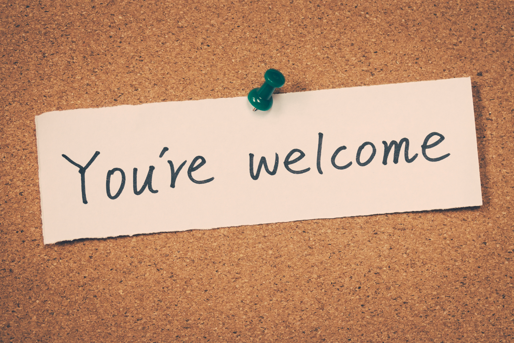 A note reading 'You're welcome' pinned on a cork board