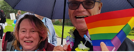 smiling woman and smiling man with rainbow flag