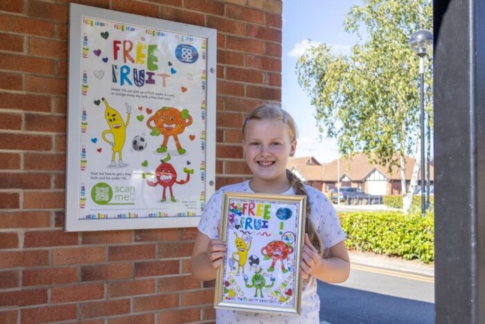 Image of Valerija-with-her-artwork-in-front-of-poster.jpg for 11-year-old’s artwork inspires healthy habits locally