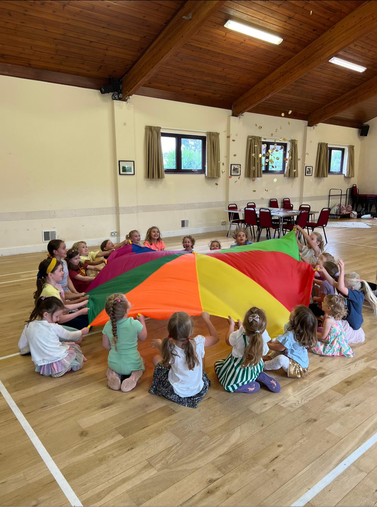 a dancer in bagg pink trousers bending over backwards with 1 hand on the ground and 1 hand reaching up above their head.
