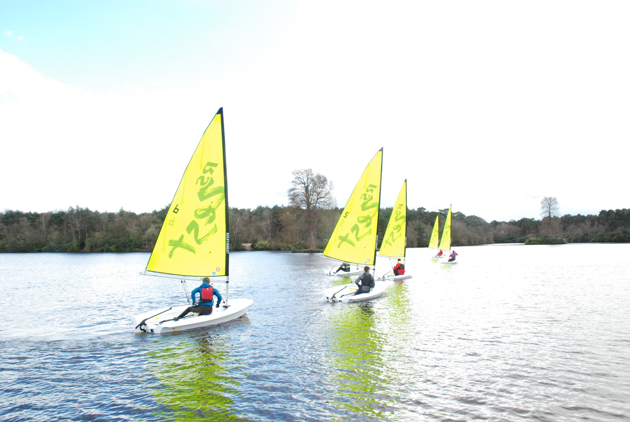 red and blue boats in a row on the water with children onboard