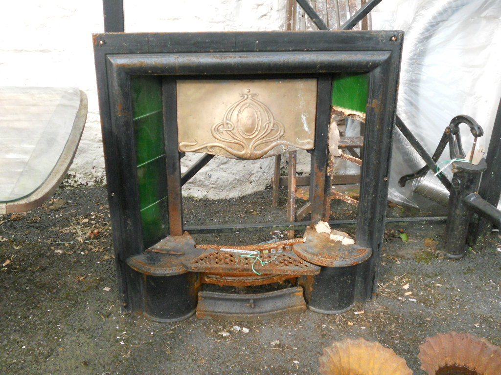 A Cast Iron Fireplace With Flanking Tiling And A Hammered Copper