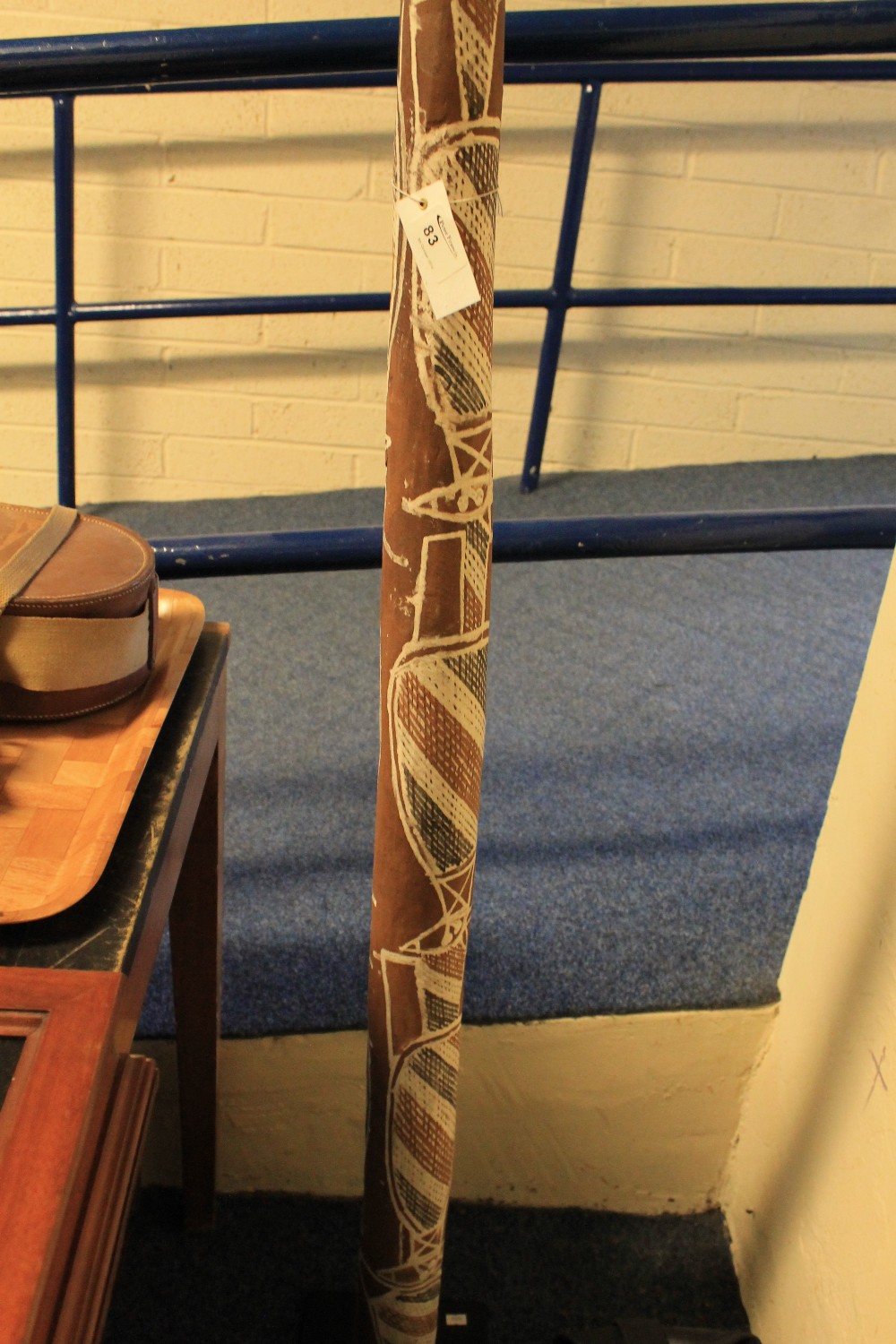 Australian painted wooden Didgeridoo on display stand.