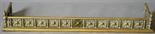AN EARLY 20TH CENTURY BRASS FENDER of typical form^ the top-rail and moulded base united by numerous