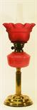 A LATE 19TH CENTURY BRASS AND GLASS OIL LAMP having a frosted cranberry glass shade with ruffled rim