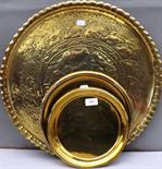 An eastern embossed brass circular tray and two other brass trays, a brass oak handled bed warming