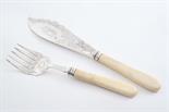 A PAIR OF EDWARDIAN IVORY HANDLED FISH CARVERS with engraved decoration, by Joseph Rogers, Sheffield