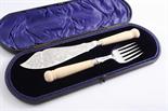 A LATE VICTORIAN CASED PAIR OF ENGRAVED FISH SERVERS with carved ivory handles, maker`s mark "TC,