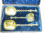 Pair of gilt-metal Serving Spoons and Sifter with pierced spiral stems and figure finials, in case