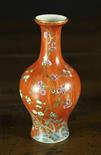 A Small Chinese Baluster Vase enamelled with pink and white prunus blossom on a brick red ground and