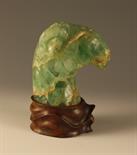 A Carved Green Rock Crystal Ram's Head mounted on a wooden base, 9 ins (23 cms) in height (A/F).