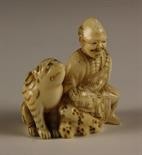 An Ivory Netsuke carved in the form of an old man sat beside a tiger dog, 1¾ ins (4.5 cms) high,