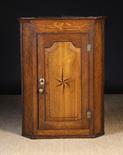 An 18th Century Oak Hanging Corner Cupboard with canted sides.  The fielded panel door inlaid with a