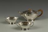 AN ART DECO THREE PIECE TEA SET of oval form, with stylised geometric decoration, wood scroll
