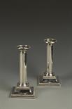 A PAIR OF CANDLESTICKS of plain column form, with beaded borders, on square bases, filled, by HE