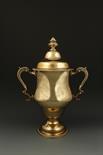 AN EDWARDIAN SILVER-GILT TWO HANDLED CUP AND COVER of baluster form, the detachable top with leaf
