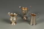 A GEORGE III CREAM JUG of helmet form, scroll handle, with bright cut engraved decoration, makers